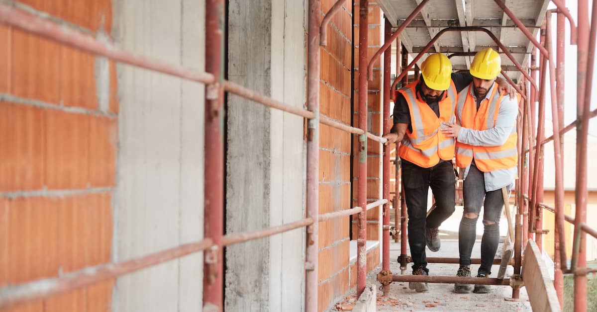 Worker helps injured colleague walk on scaffolding. | Colling Gilbert Wright